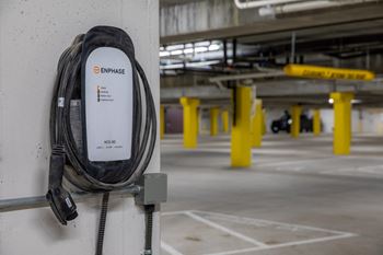 an electric cable plugged into a wall in a parking garage